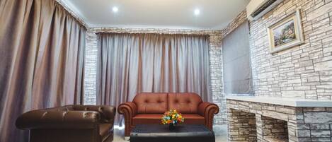 A living room with a brown leather sofa, a matching ottoman, and a stone fireplace.