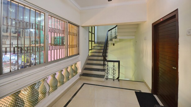 A staircase with a metal railing, a wooden door, and a window with metal bars. - OYO 7337 Sai Leela (Puri)
