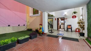A hotel lobby with a tiled floor, a reception desk, a statue, potted plants, and a staircase. - OYO 7337 Sai Leela (Puri)