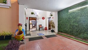 A reception area with a tiled floor, a green wall, a statue, and a potted plant. - OYO 7337 Sai Leela (Puri)