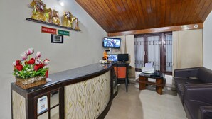 A reception area with a wooden ceiling, a reception desk with a 'paytm' sign, a TV, and a flower arrangement. - OYO 7337 Sai Leela (Puri)