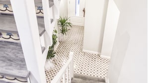 Una escalera con barandillas blancas y piso a cuadros que lleva a una puerta.
