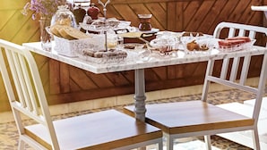 Una mesa con diversos pasteles y bebidas, un campanario al fondo y vistas de la ciudad.