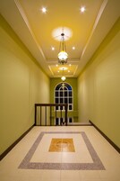 A hallway with a tiled floor, a staircase with a railing, and a ceiling light fixture.