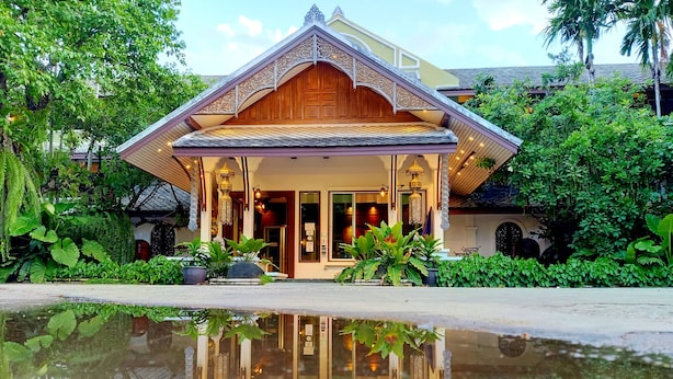 A traditional building with a wooden facade, large windows, and a reflection in the water in front.