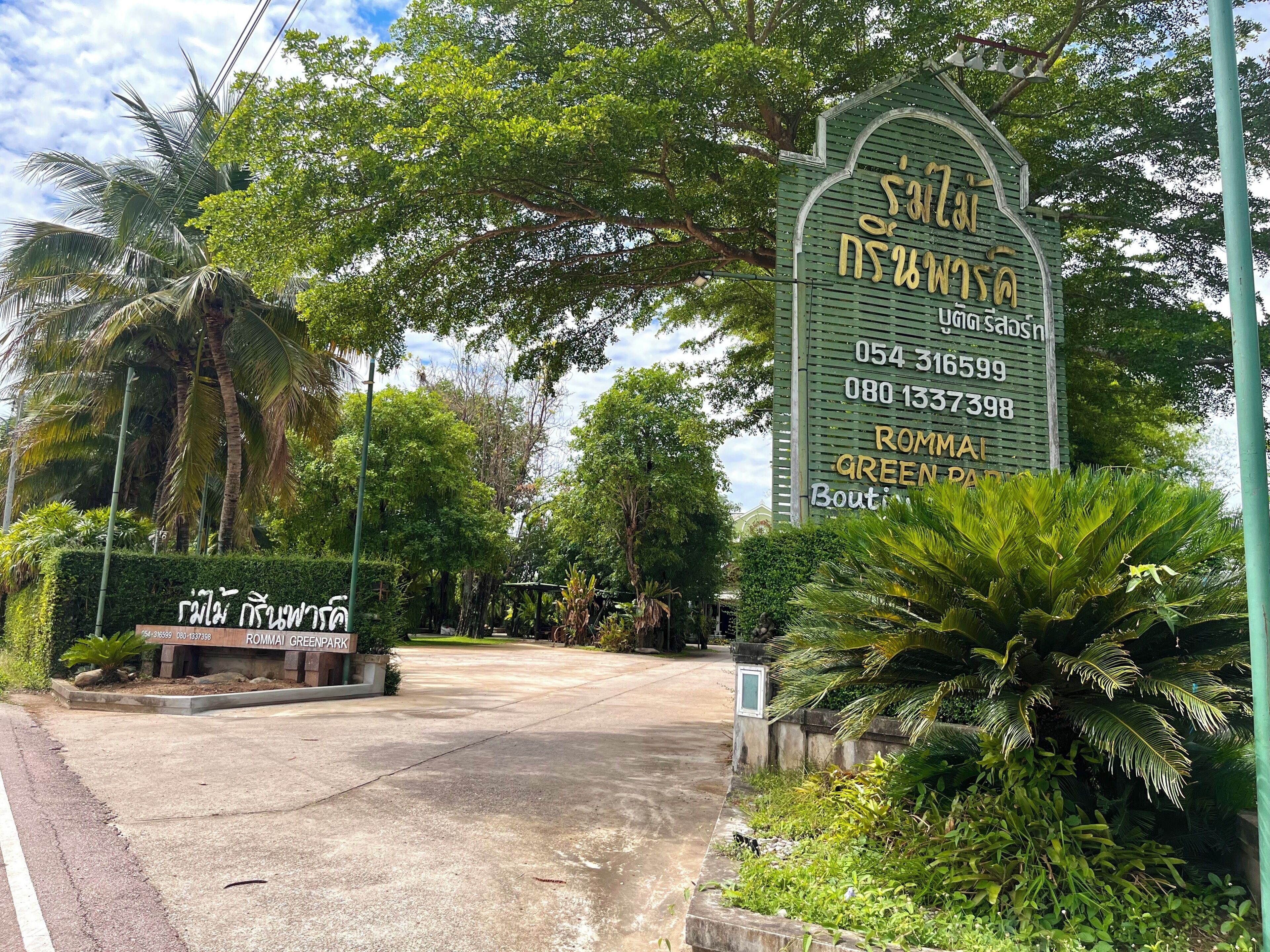 A sign for Rommai Green Park with contact numbers and a paved entrance.