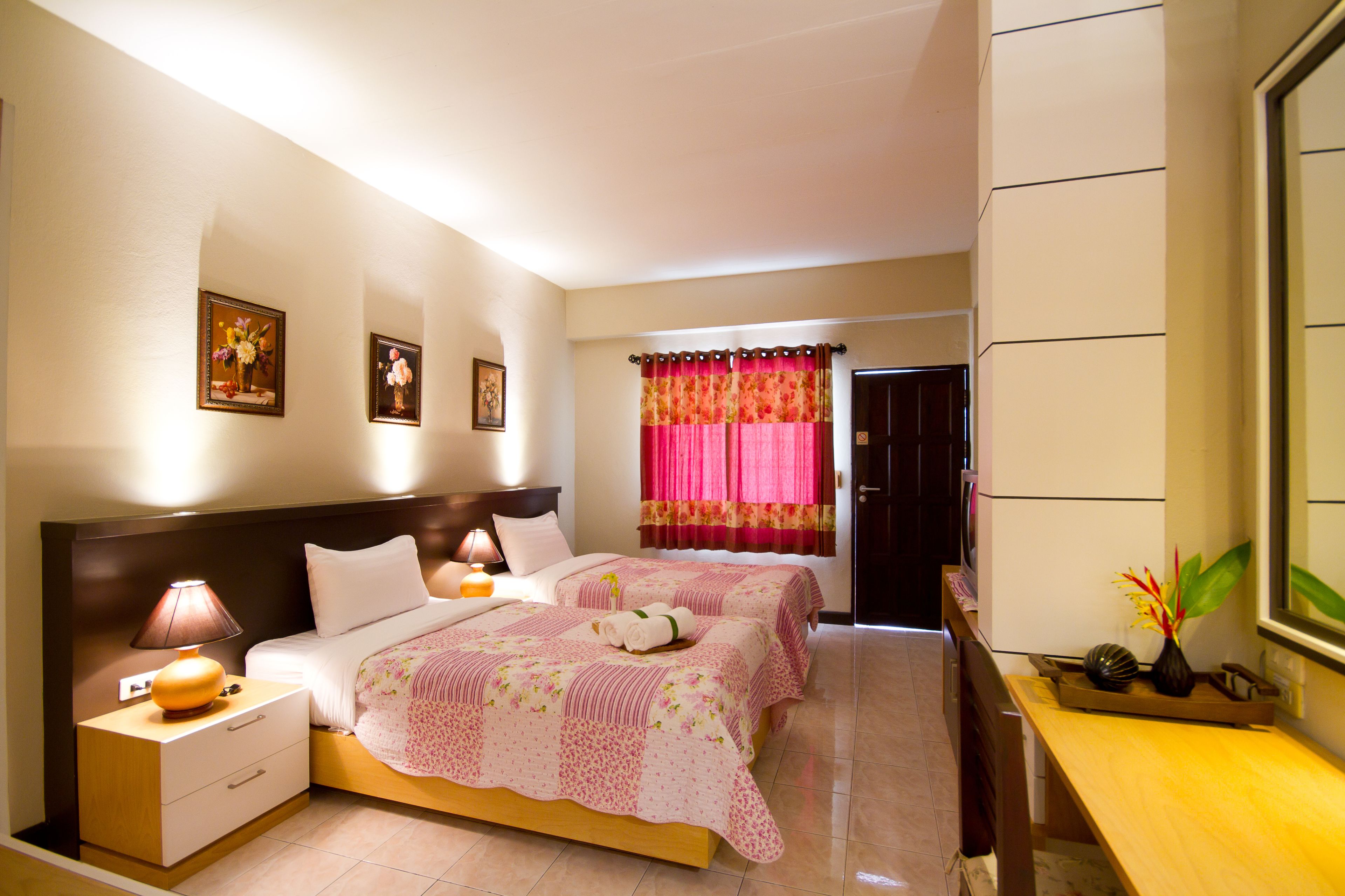Une chambre d’hôtel avec deux lits, une table de chevet, une lampe, une commode et un miroir.