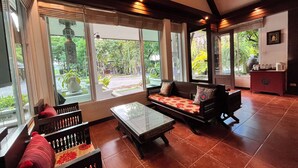 A spacious room with a large window, a sofa set, a coffee table, and a cabinet.