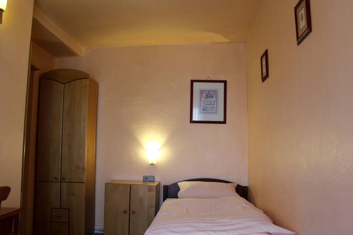 A bedroom with a bed, a wardrobe, and a wall-mounted light.