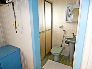 A small bathroom with a toilet, sink, and shower.