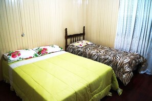 A small bedroom with two single beds, one with a floral bedspread and the other with a zebra print bedspread.