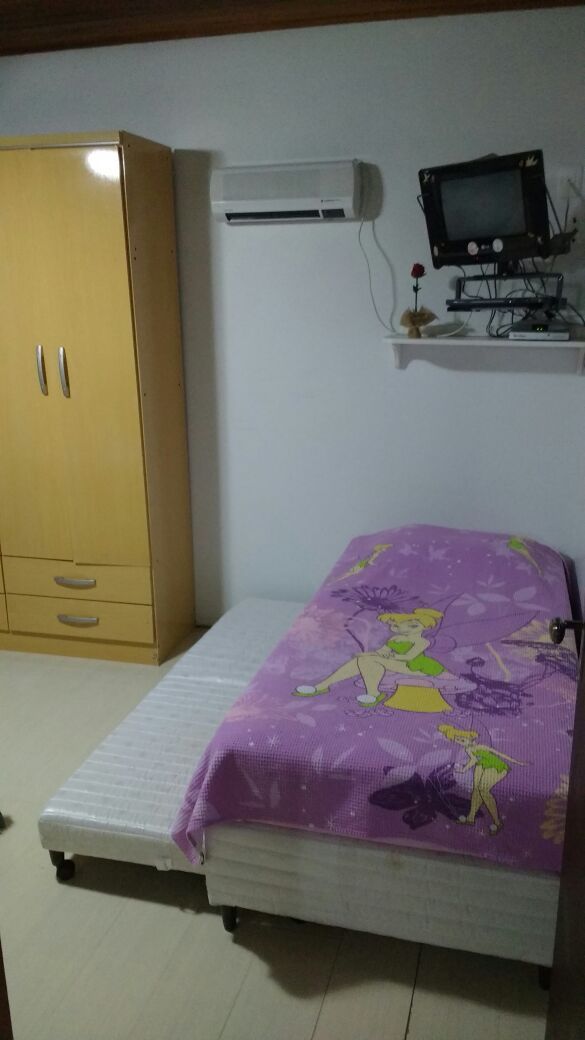 A bedroom with a bed, a wardrobe, an air conditioner, and a television.