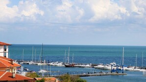 A marina with boats docked, a clear sky, and a calm sea. - Panorama Fort Beach Complex (Sveti Vlas)