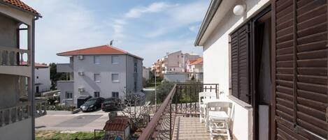 A residential area with a balcony, a garage door, and a parked car.