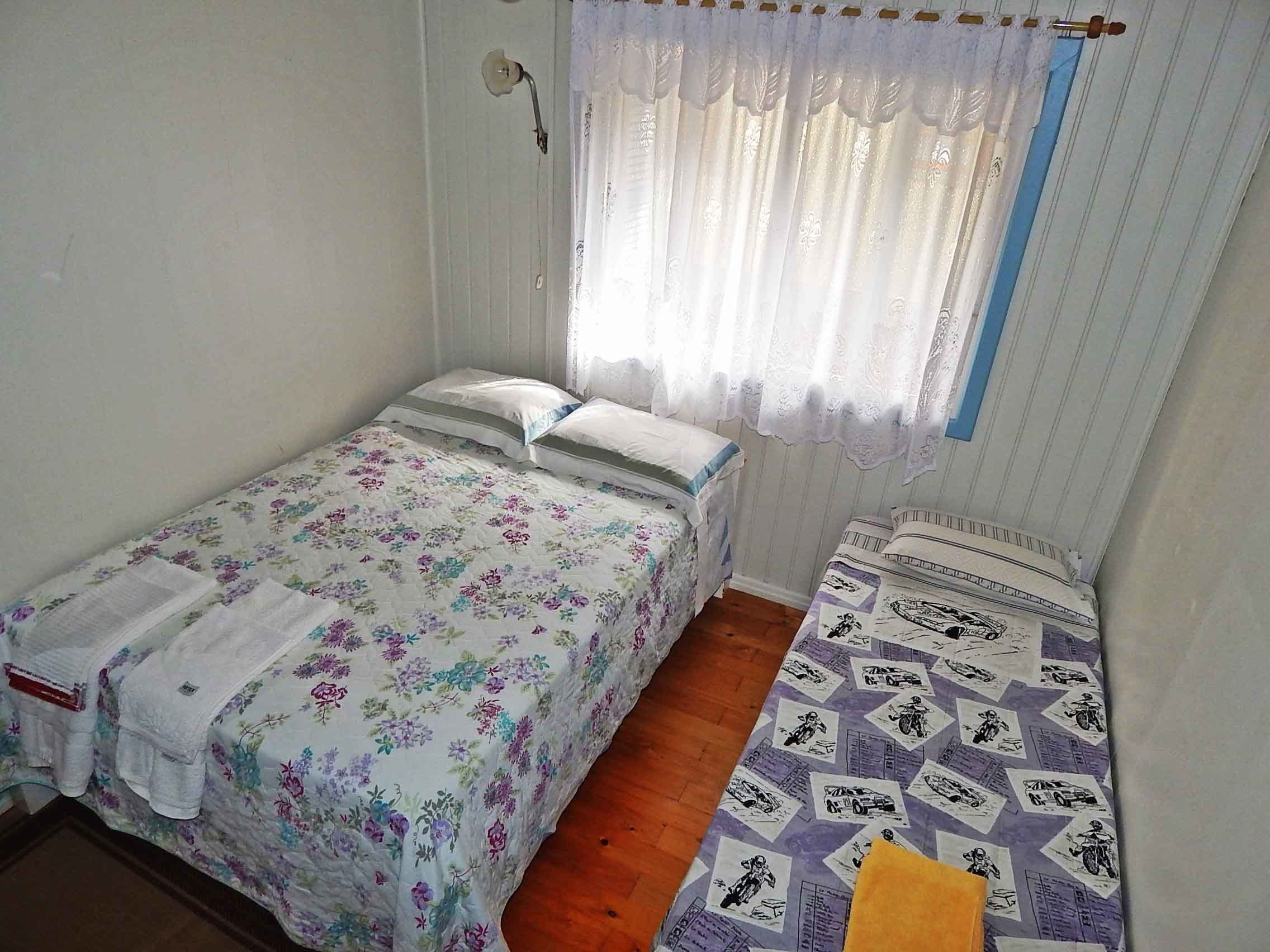 Een slaapkamer met twee bedden, waarvan één met bloemenbeddengoed en de ander met een gestreept beddegoed.