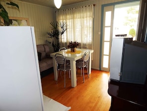 Cozy living space with a dining area, featuring a table and chairs, a potted plant, and a TV on a cabinet.