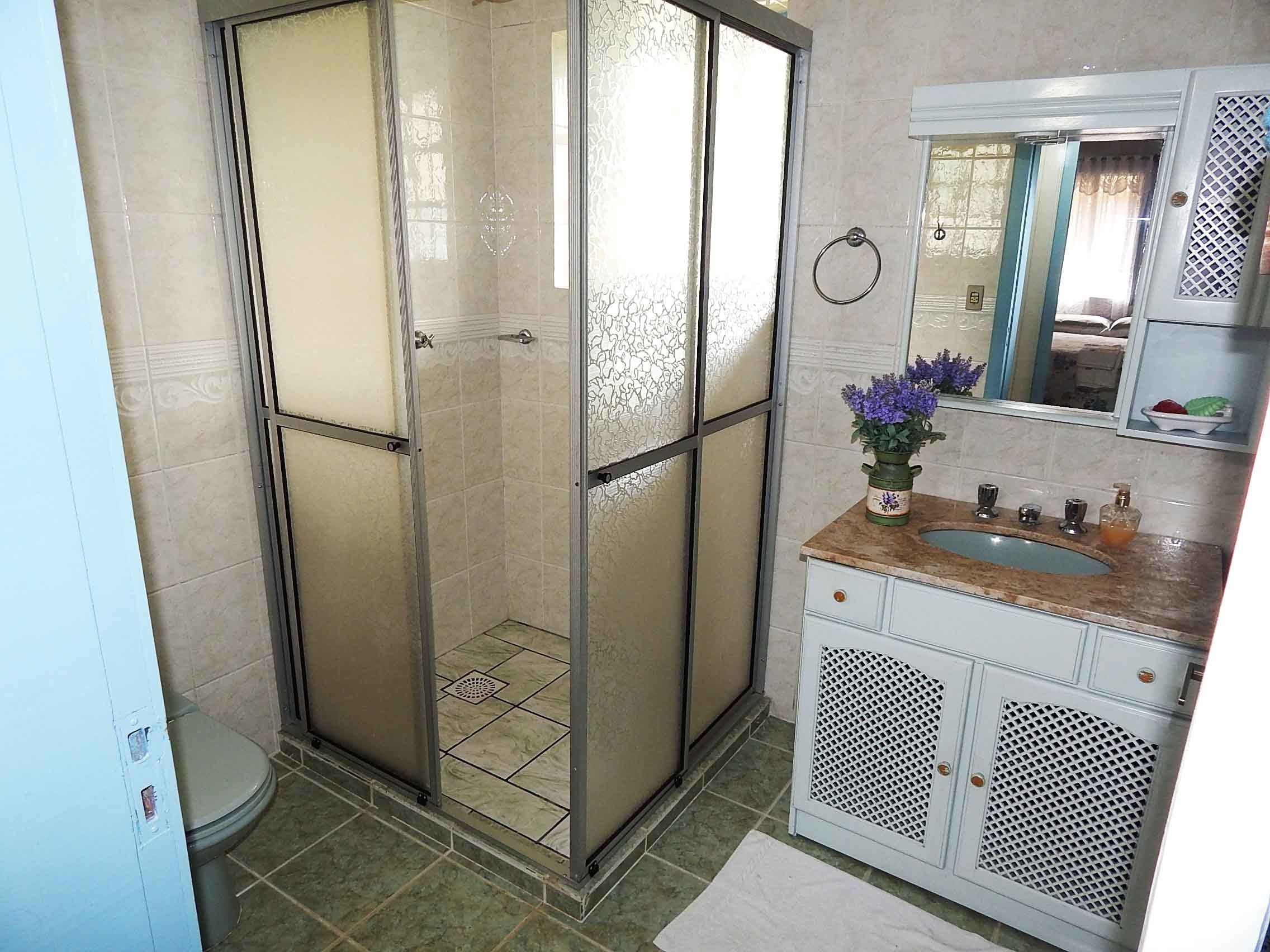 A bathroom with a glass-enclosed shower, a sink with a mirror, and a toilet.