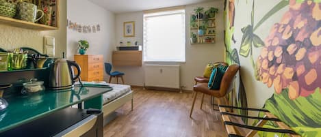 A compact living space with a kitchenette, a dining area, and a large window providing natural light.
