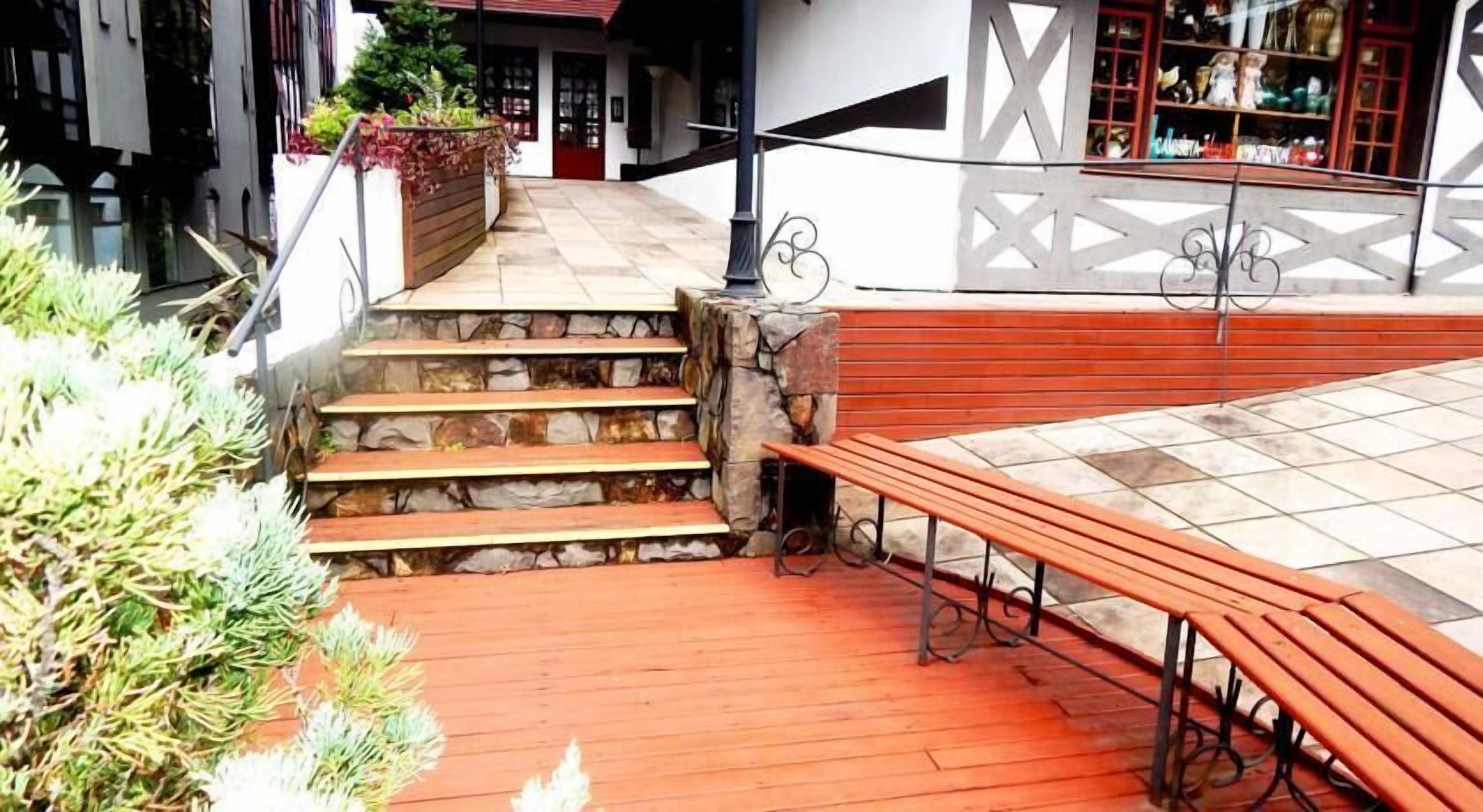 Un escalier en pierre mène à une terrasse en bois dotée de bancs.