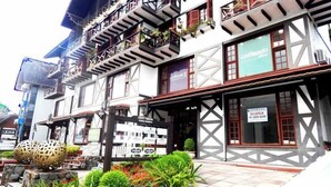 A traditional building with a balcony, a sign for 'unifocado Med', and a 'CRABADO ALUGA' sign. - Apartamento da Borges (Gramado)