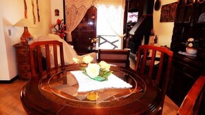 Un coin repas avec une table ronde en bois, des chaises et un vase rempli de fleurs.
