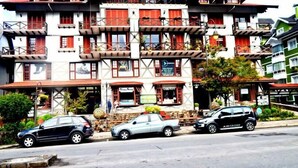 Un immeuble à plusieurs étages doté de balcons, d’une devanture de magasin et de voitures garées dans la rue.