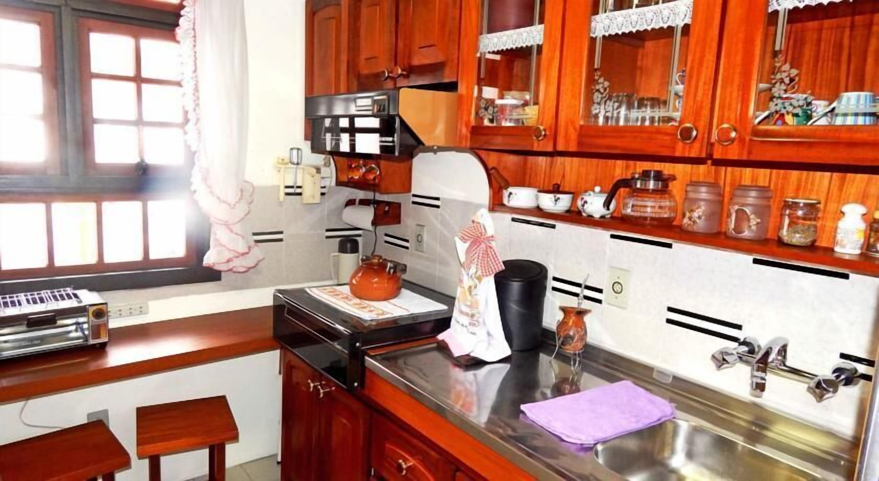 A kitchen with wooden cabinets, a stove, a sink, and various kitchen items.