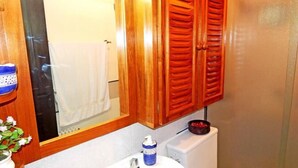 A bathroom with wooden cabinets, a white towel hanging, a blue bottle, and a small plant. - Apartamento da Borges (Gramado)