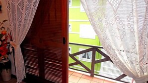 A balcony with a wooden railing and a view of a green building. - Apartamento da Borges (Gramado)