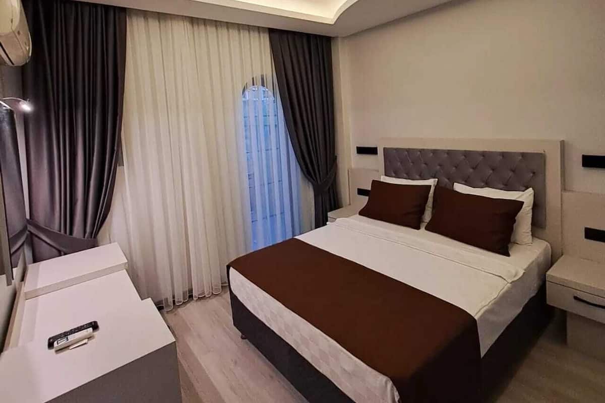 Quarto de hotel moderno com uma cama grande, uma escrivaninha e um lustre.