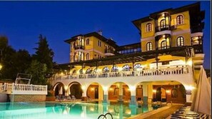 A large, multi-story hotel with a swimming pool, outdoor seating, and a covered patio area. - Altinsaray Hotel (Kusadasi)