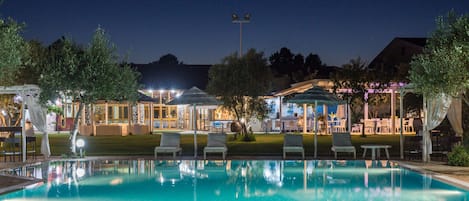 Una piscina al aire libre, sillones reclinables de piscina