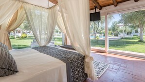 A bedroom with a large bed, sheer curtains, and a view of a well-maintained garden. - Da Renzo (Siamaggiore)