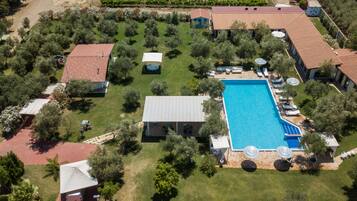 An aerial view of a property with a swimming pool, multiple buildings, and a vineyard in the background.