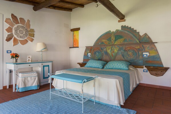 Un dormitorio con cama, mesitas de noche, un escritorio y una silla.