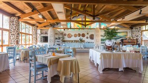 A spacious dining area with high wooden ceilings and stone walls, featuring multiple tables and chairs. - Da Renzo (Siamaggiore)
