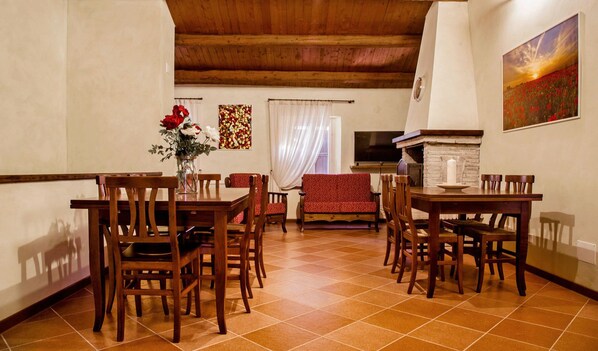 A dining area with wooden furniture, a fireplace, and a painting on the wall. - Naturaverde Country House (Senigallia)