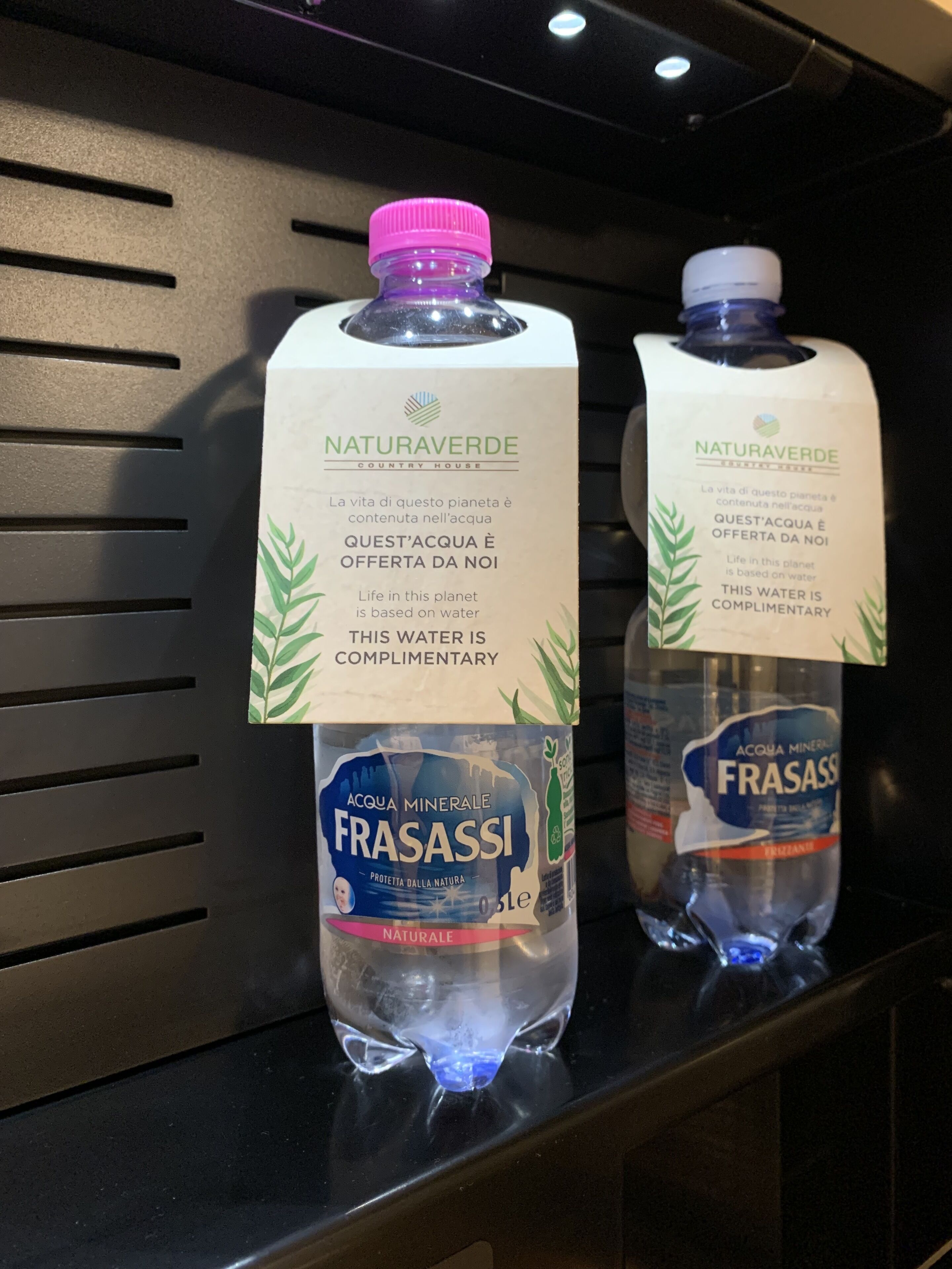 Hyllyllä on kaksi vesipulloa, joiden etiketissä lukee ’Naturaverde’ ja ’Frasassi’.