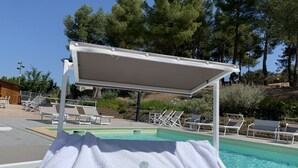 Ein Poolbereich mit Liegestühlen und einer überdachten Sitzgelegenheit.