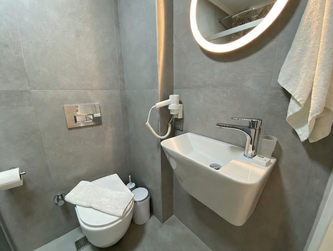 A modern bathroom with a toilet, sink, and mirror.