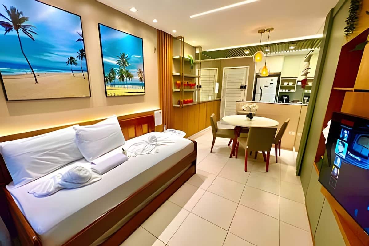 Une chambre d’hôtel comprenant un lit, un coin repas, une cuisine et des œuvres d’art accrochées aux murs.