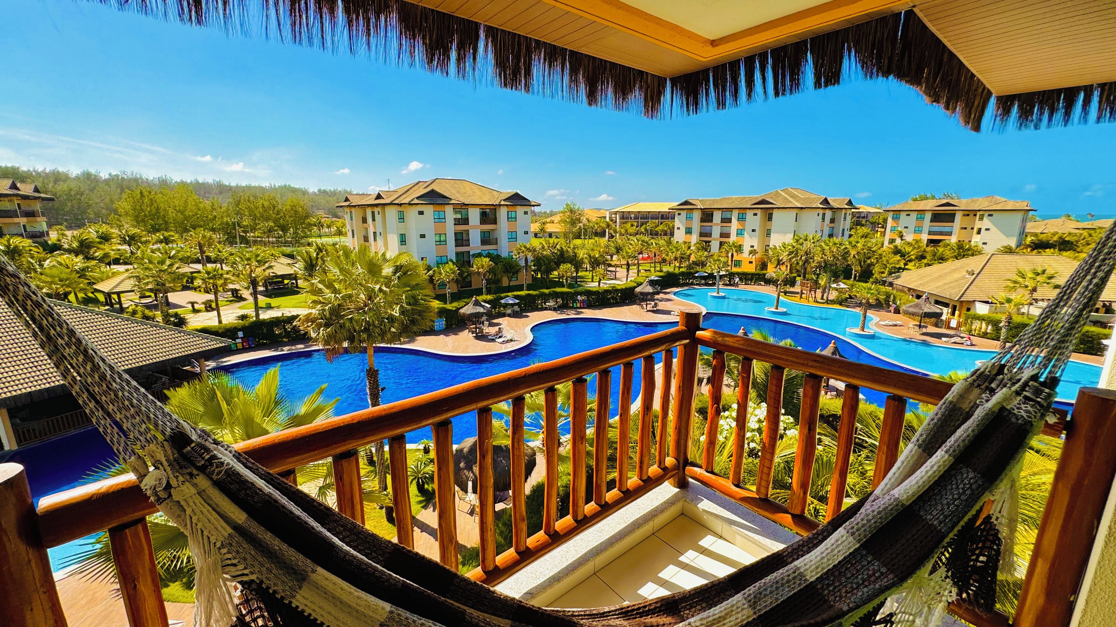 A resort with a large swimming pool, multiple buildings, and lush greenery.