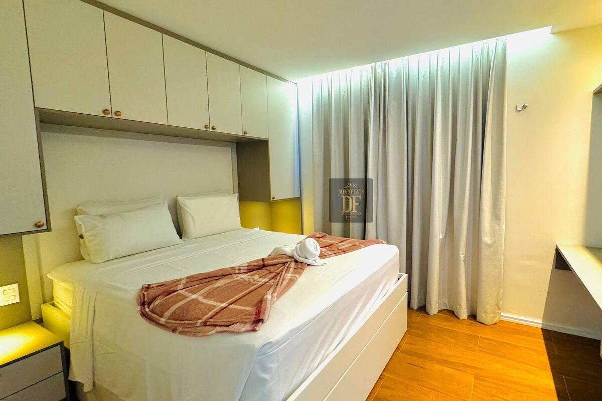 Une chambre d’hôtel avec un lit, une table de chevet, une télévision et une fenêtre avec des rideaux.