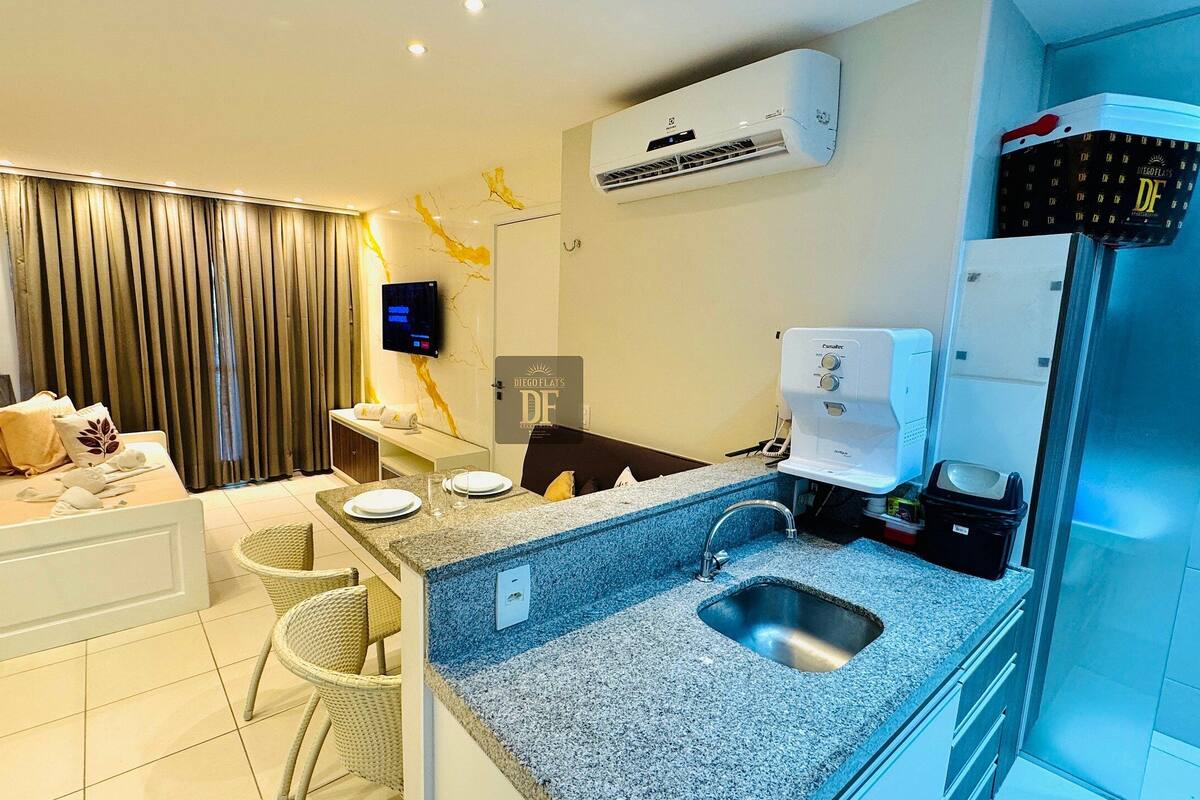 Une chambre d’hôtel moderne dotée d’une kitchenette, d’un coin repas, d’une télévision et d’un espace douche.