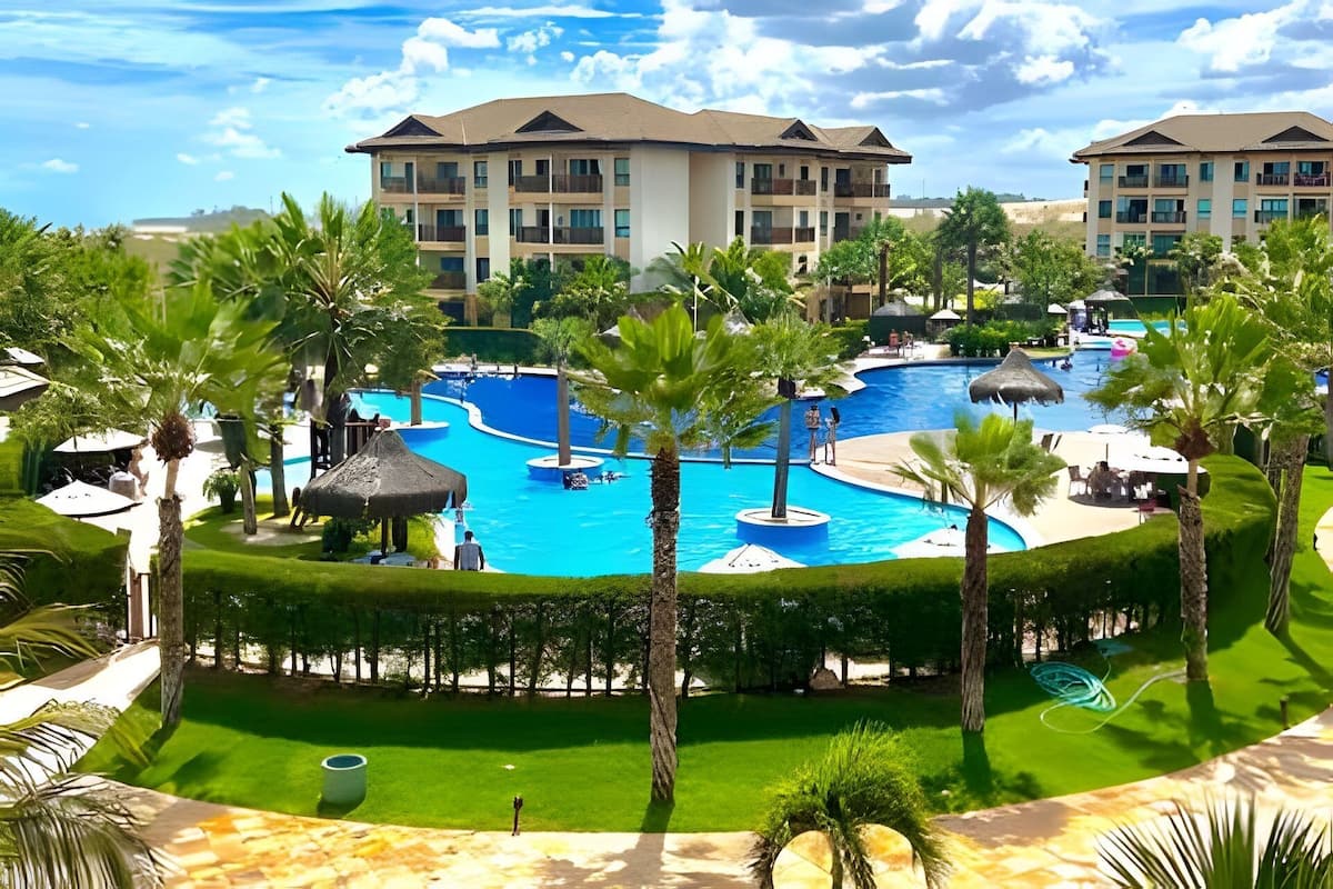 Un hôtel doté de nombreux balcons, d’une piscine centrale et entouré de palmiers.