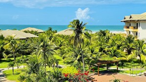 Un resort con estructuras de techo de paja, palmeras y vista al océano.