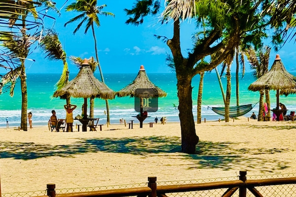 Na praia, areia branca, barracas de praia de cortesia, espreguiçadeiras