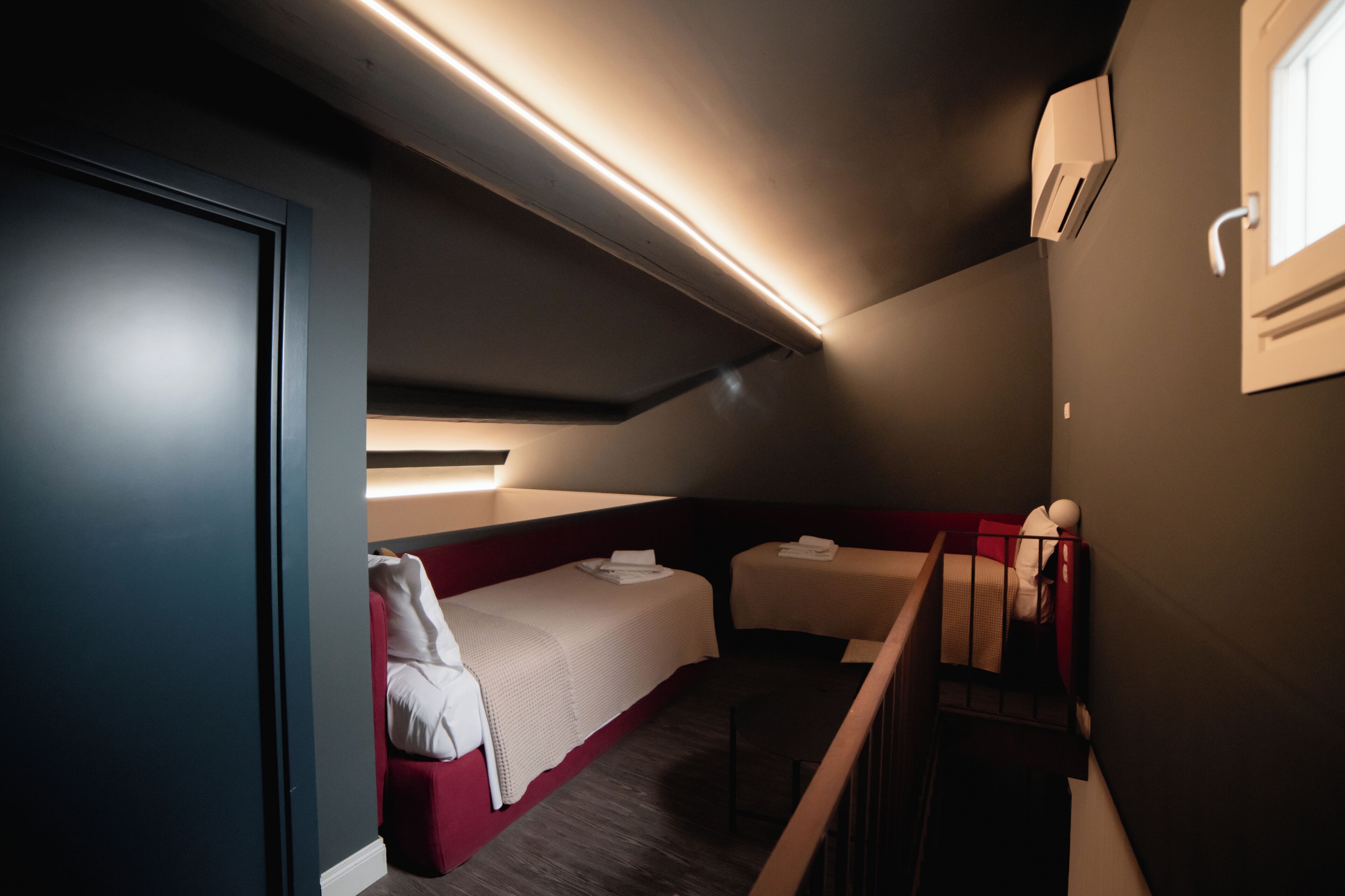 A compact hotel room with a bunk bed, a small desk, and a window.