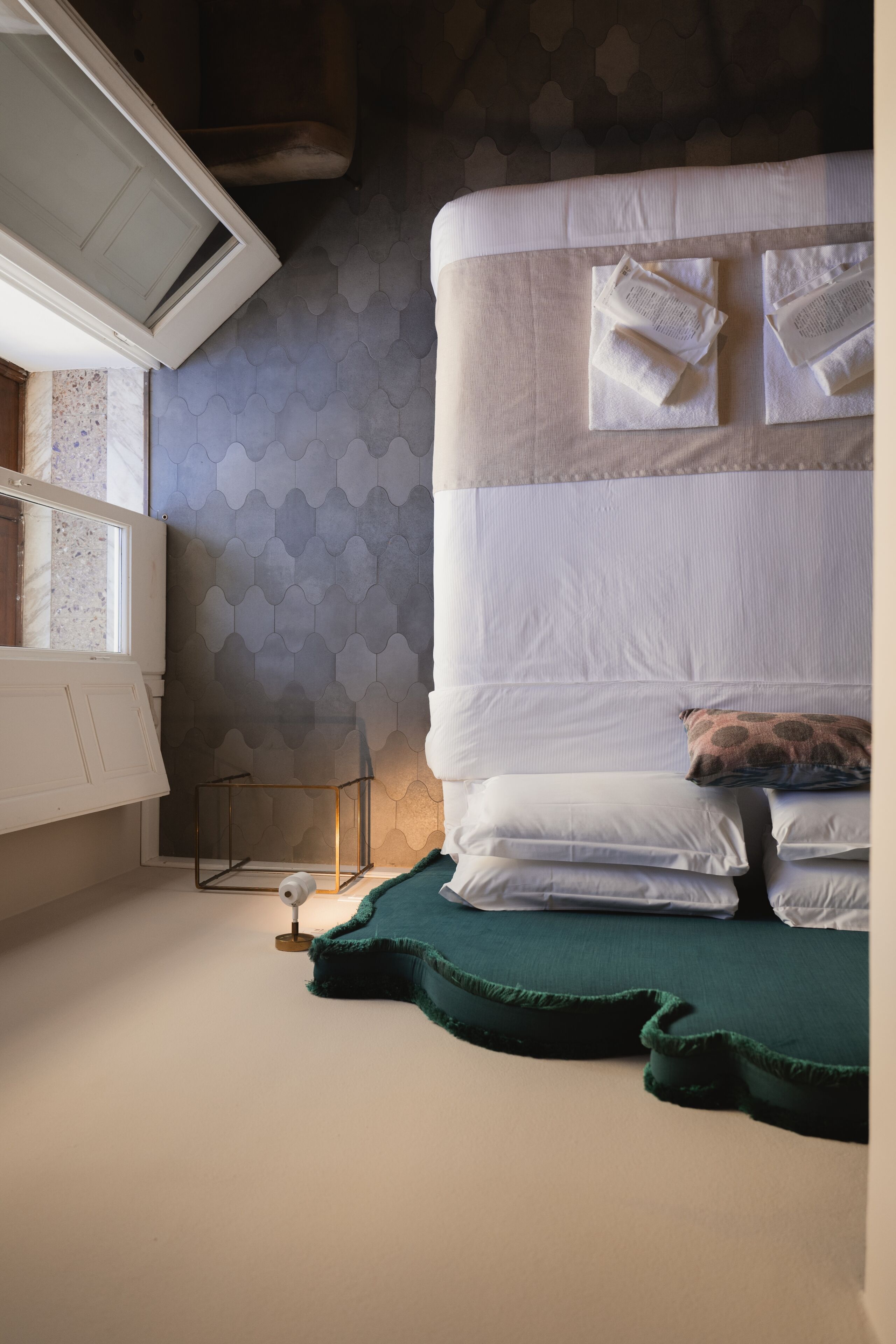 Una habitación de hotel con una cama, una toalla verde y una ventana con vistas al exterior.