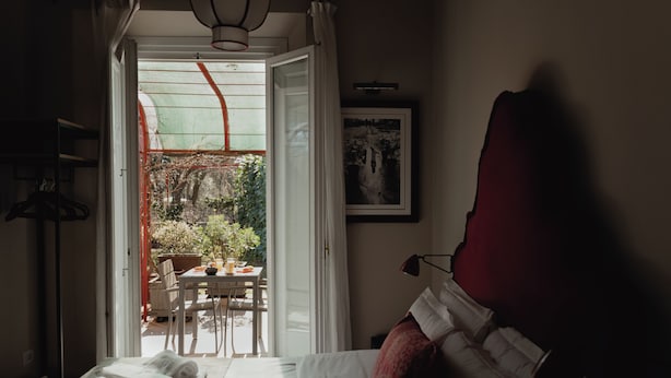 Habitación de hotel con una cama, una mesa y sillas frente al ventanal.